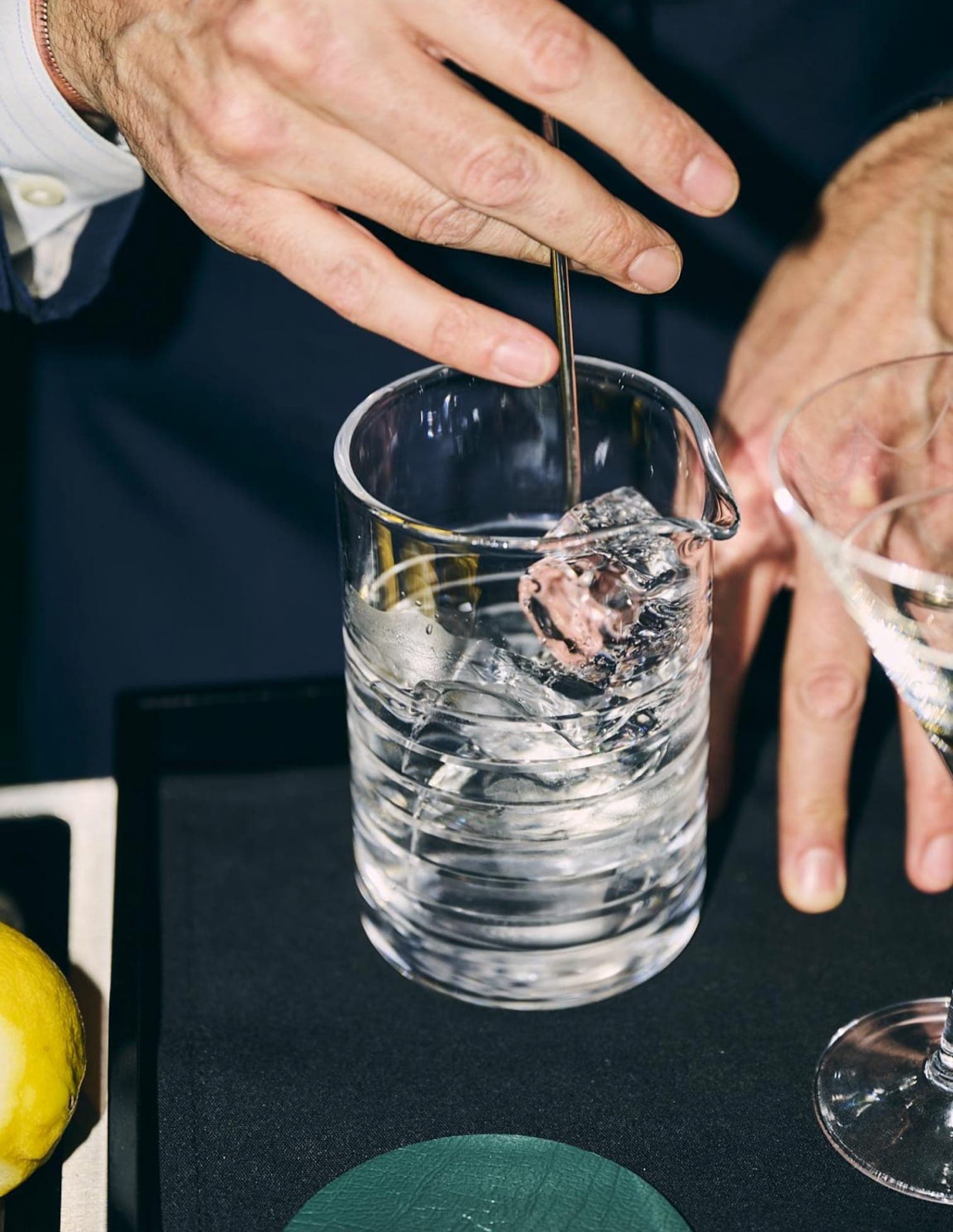 A cocktail is stirred with ice in a cocktail mixing glass.