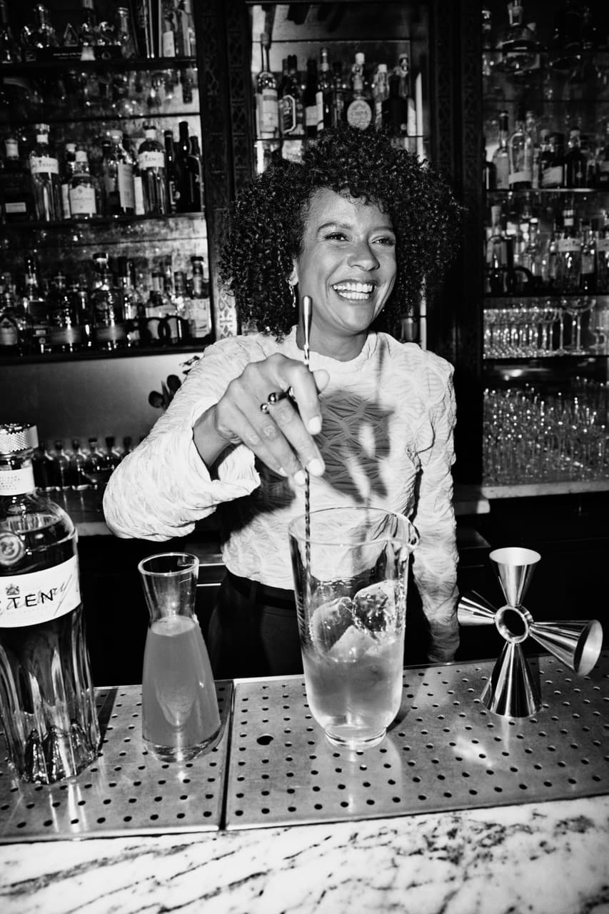 Jenna Ba standing behind a bar mixing a cocktail