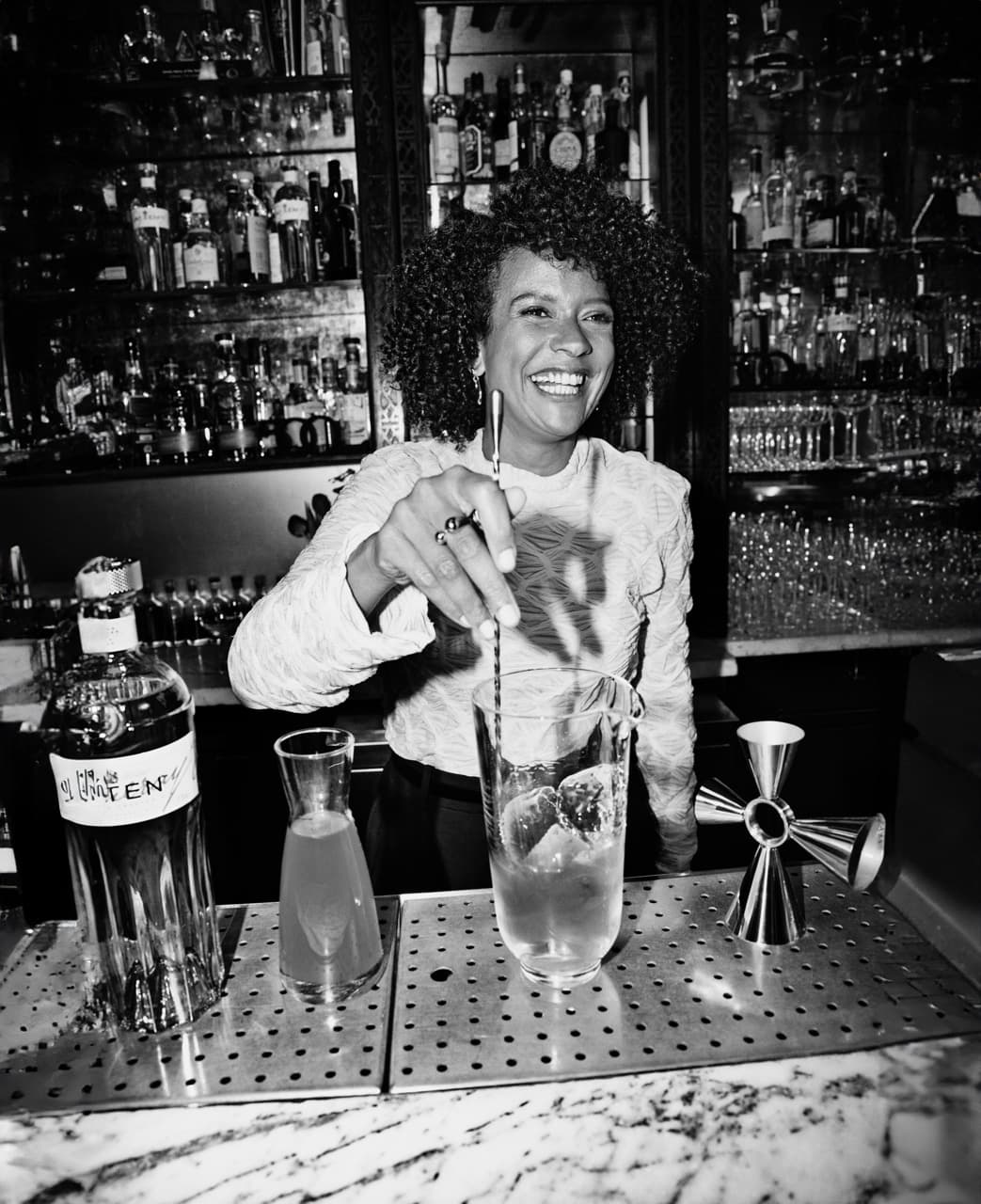 Juila Ba smiling and mixing a cocktail.