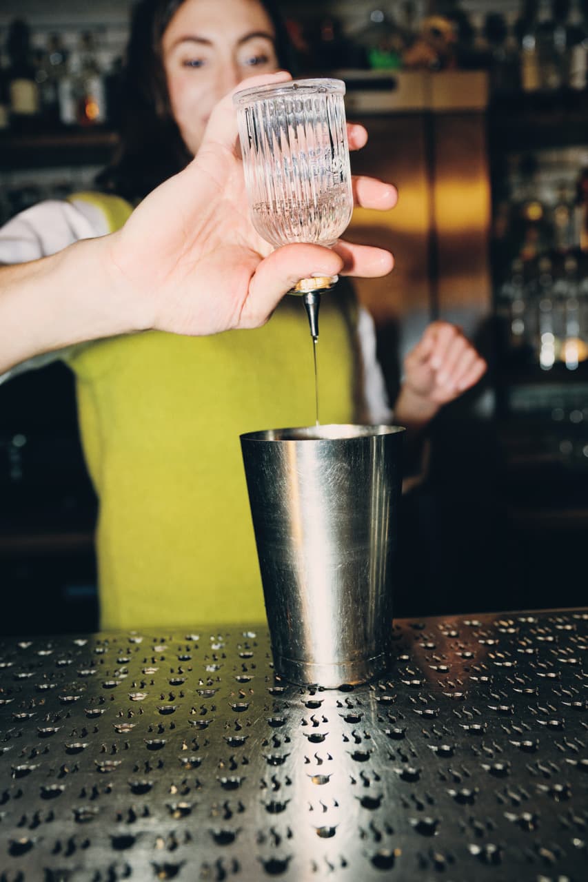 Liquid is poured into a cocktail shaker.