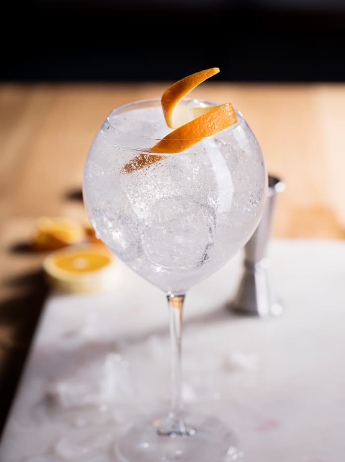 A close up of a Tanqueray 0.0% Alcohol Free Spirit and Tonic with Orange Peel cocktail in a glass