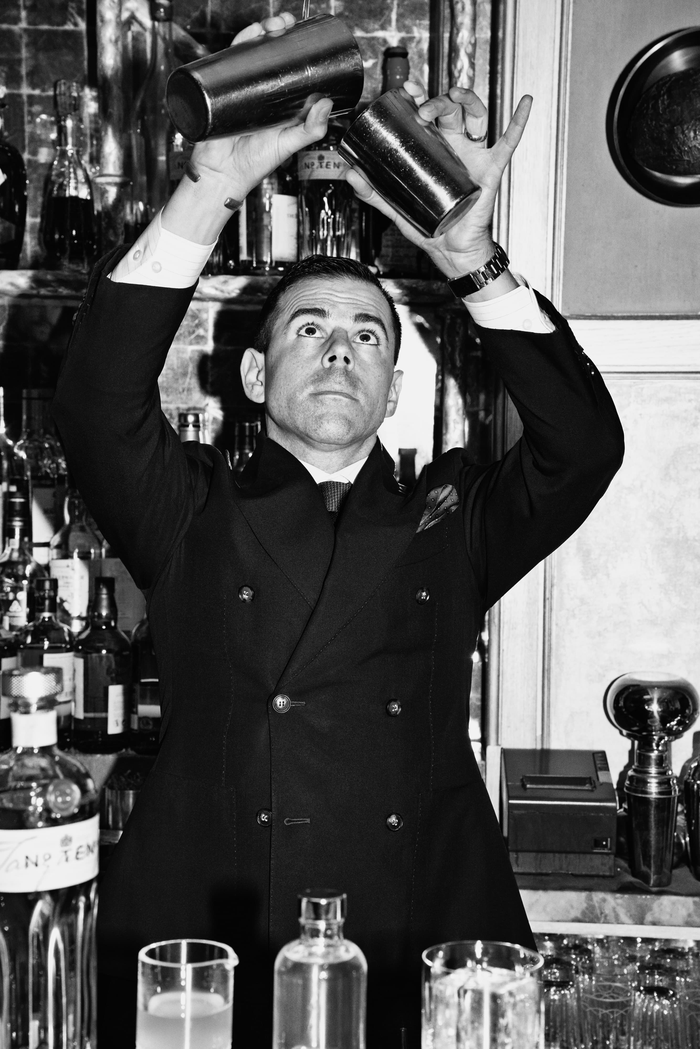 Ago Perrone pouring tanqueray into a cocktail shaker.