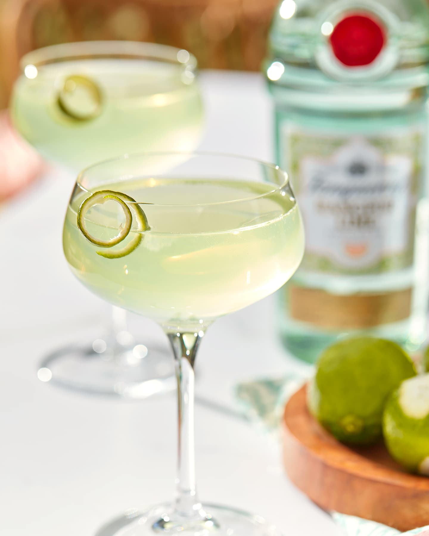 A light green Tanqueray Rangpur Gimlet cocktail in a glass garnished with a lime swirl.