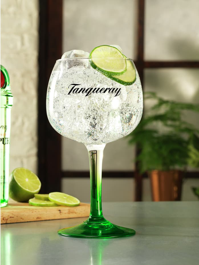 A Gin & Tonic cocktail made with Tanqueray Ranpur and garnished with lime slices.