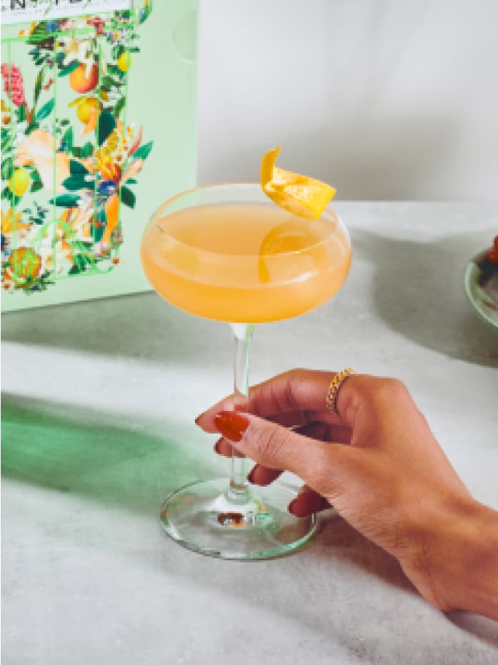 A hand holding a Grapefruit Martini cocktail made with Tanqueray No. Ten Gin